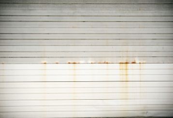 Close-up of a white sectional garage door with visible rust stains and dirt buildup, highlighting the need for routine garage door maintenance in Casselberry, FL.
