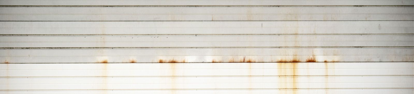 Close-up of a white sectional garage door with visible rust stains and dirt buildup, highlighting the need for routine garage door maintenance in Casselberry, FL.