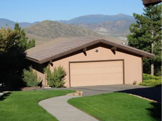 New Garage Door Installation – Casselberry FL Detached garage with a newly installed beige sectional garage door, surrounded by lush green landscaping and mountain views in Casselberry, FL.