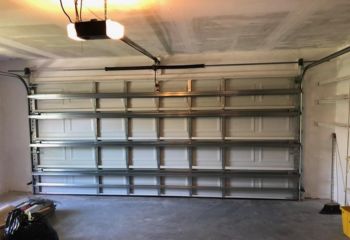 Interior of a clean Longwood, FL garage with a newly installed Craftsman 57918 garage door opener and a white sectional garage door.