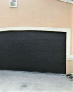 Newly installed dark, modern garage door with a smooth finish and precise fit on the same Casselberry home.