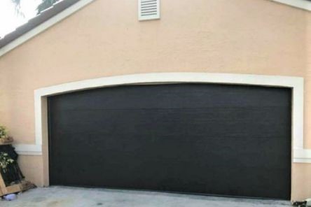 Newly installed dark, modern garage door with a smooth finish and precise fit on the same Casselberry home.