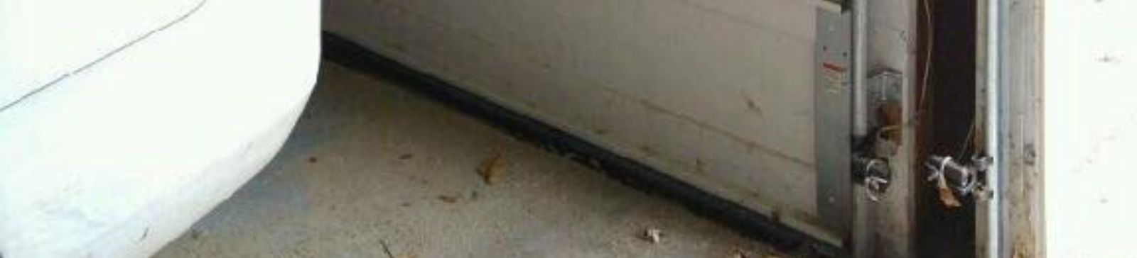 Interior view of a Casselberry garage with a white sectional garage door and visible safety sensors near the track, showing the door now closing properly after sensor realignment.