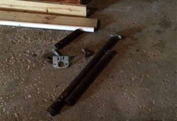 Broken and removed garage door torsion spring pieces lying on a concrete garage floor next to installation tools in Fern Park, FL.