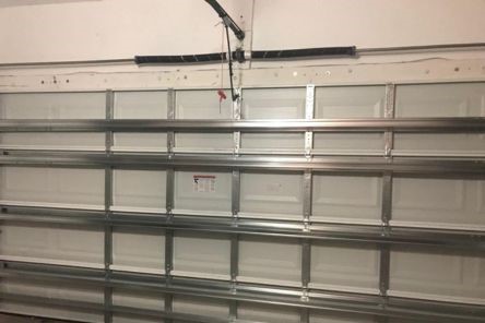Interior view of a fully installed and reinforced garage door with new torsion springs and metal supports in a Winter Springs home.
