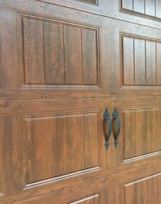 Close-up of a newly installed wood-look garage door with vertical panels and black decorative handles on a Longwood, FL home.