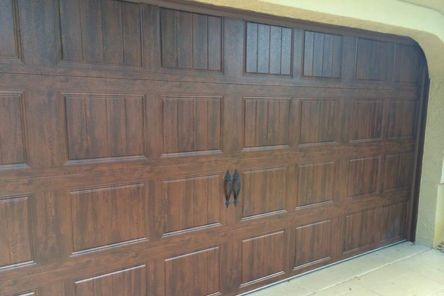 Angled exterior shot of the wood-grain garage door under an arched entryway, highlighting the realistic finish and upgraded hardware in Longwood, FL.